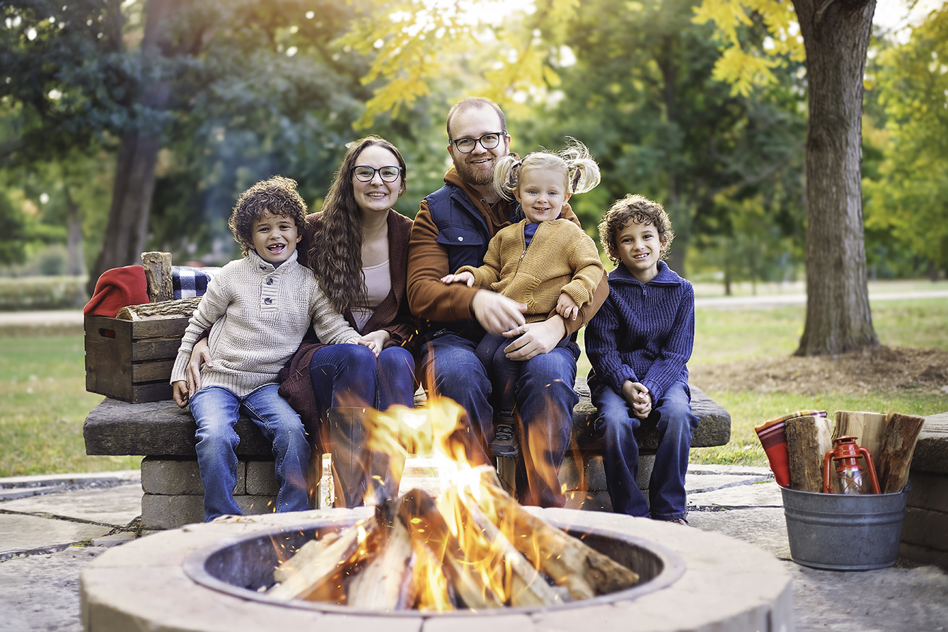 Family gathered around a campfire during a summer photography session in Bloomington Illinois